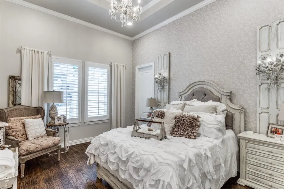Bedroom with plantation shutters, a tray ceiling and a crystal chandelier