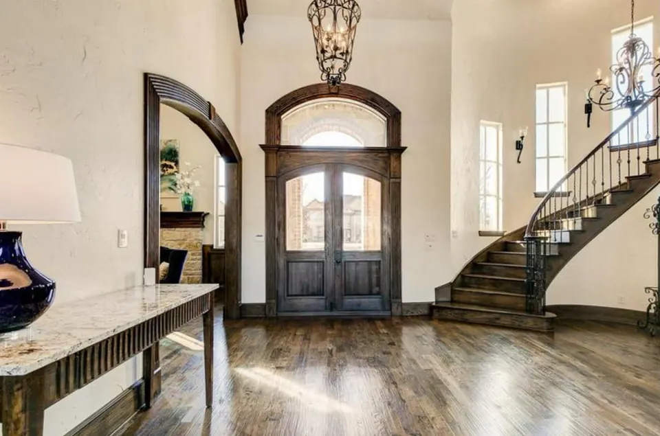 Entry hall with arched wood doors, a curved iron staircase and wood floors