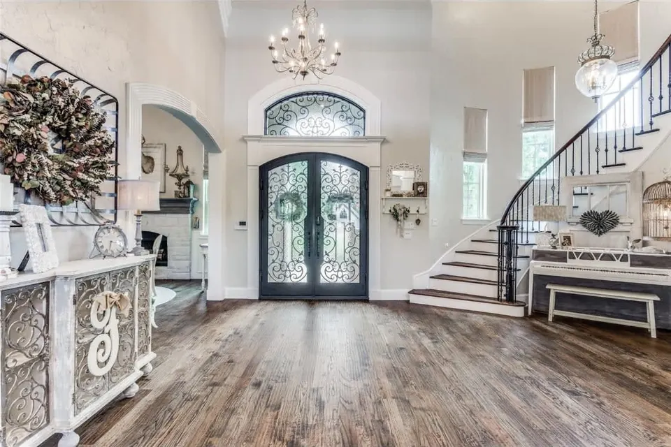 Two-story foyer with iron entry doors, a curved staircase and wide plank wood floors