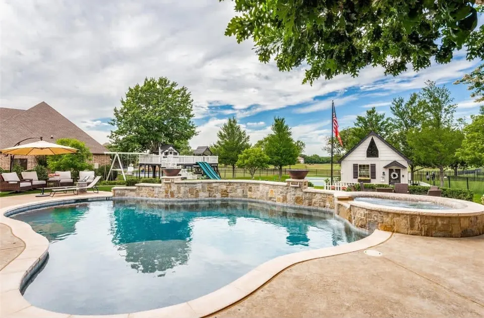 Free-form pool with a raised stone spa wall and a lawn beyond