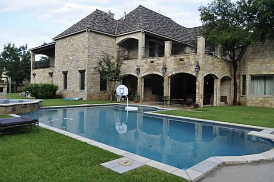 Stone home with an arched lower loggia and balconies above a rectangular pool