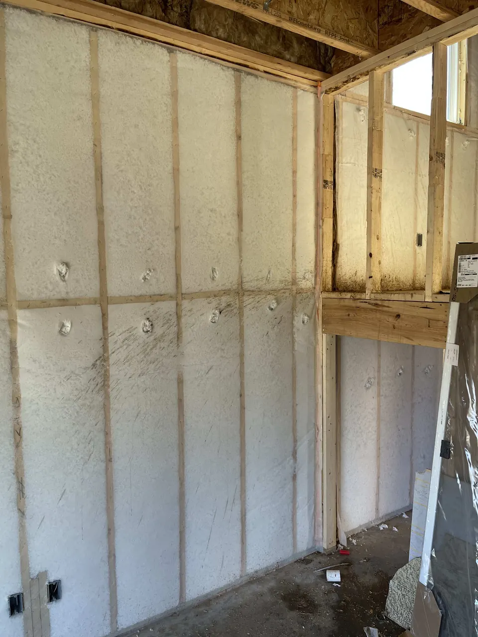 Spray foam insulation between the studs of a framed room
