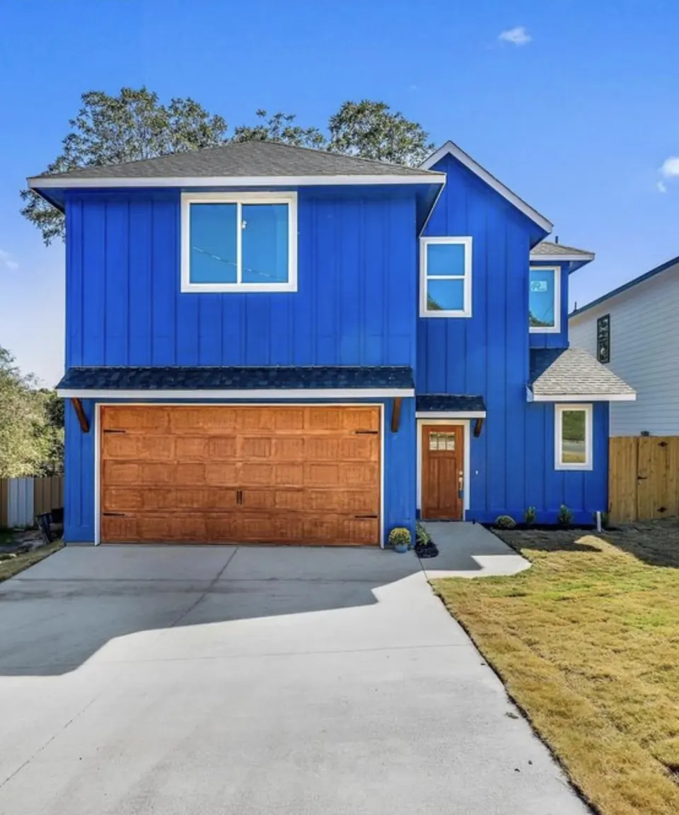 Blue two-story home with board-and-batten siding and a wood garage door
