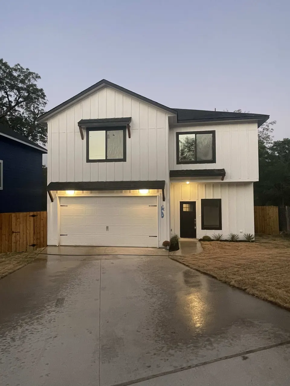White two-story home with the garage and porch lit at dusk