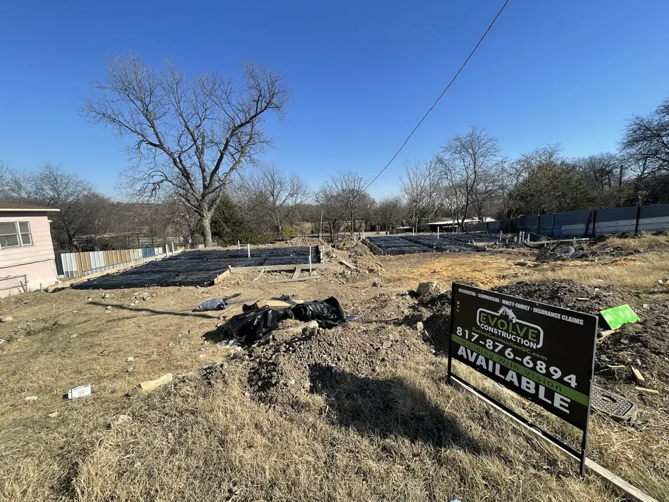 Prepared lot with foundation forms in place and an Evolve Construction sign reading Available