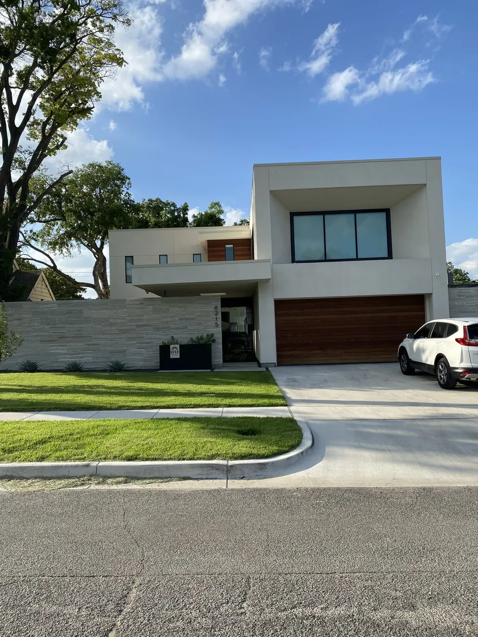 Modern two-story home with white stucco volumes and a wood garage door