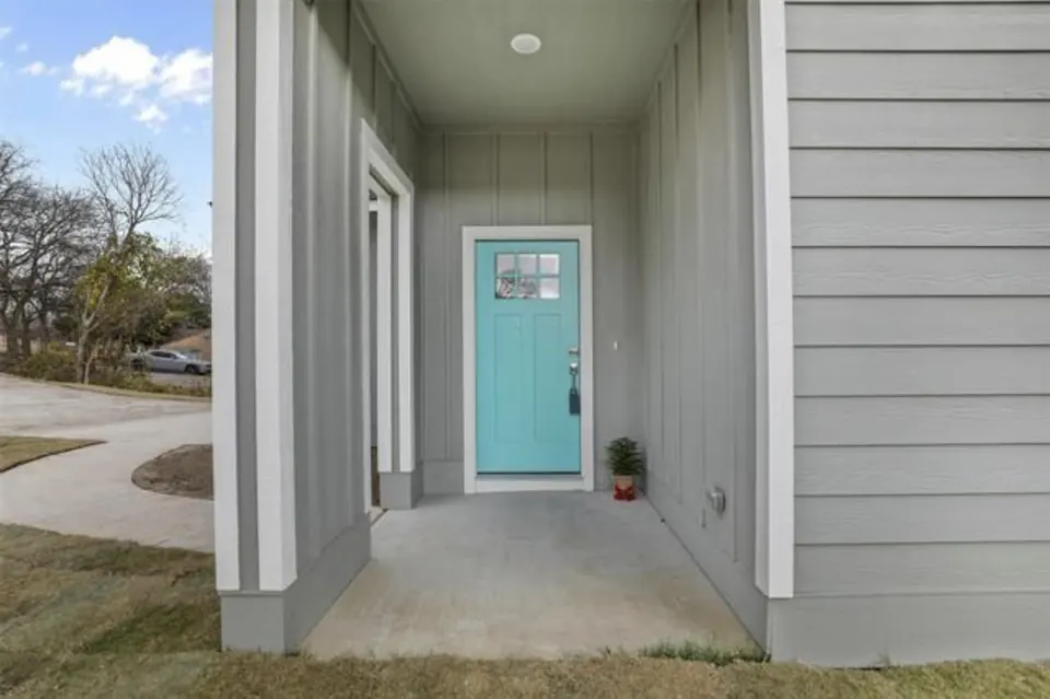 Covered entry porch with a teal front door and gray lap siding