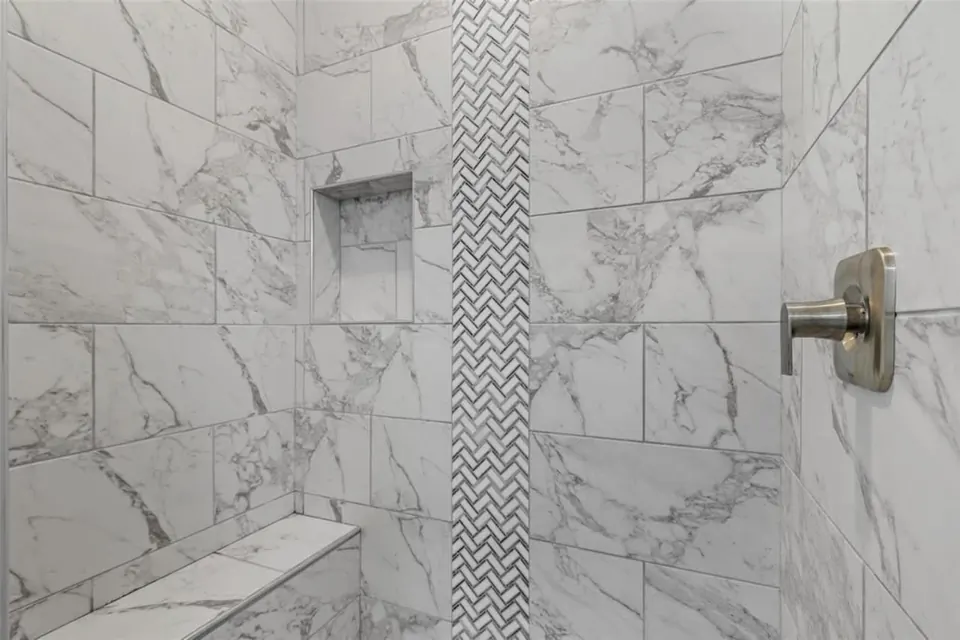 Marble-look tile shower with a niche and a herringbone accent strip