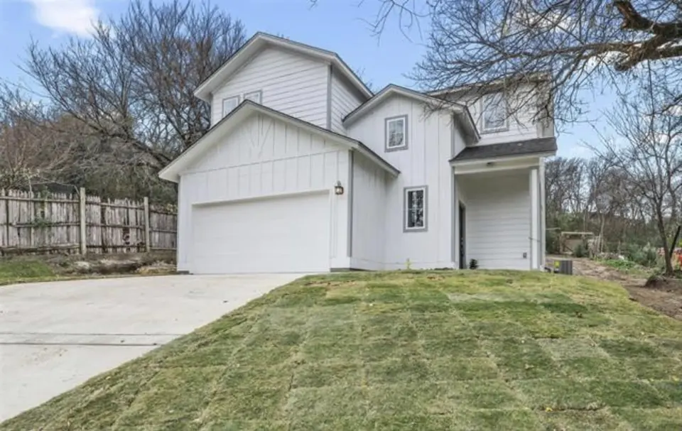 White board-and-batten two-story home with a two-car garage and new sod